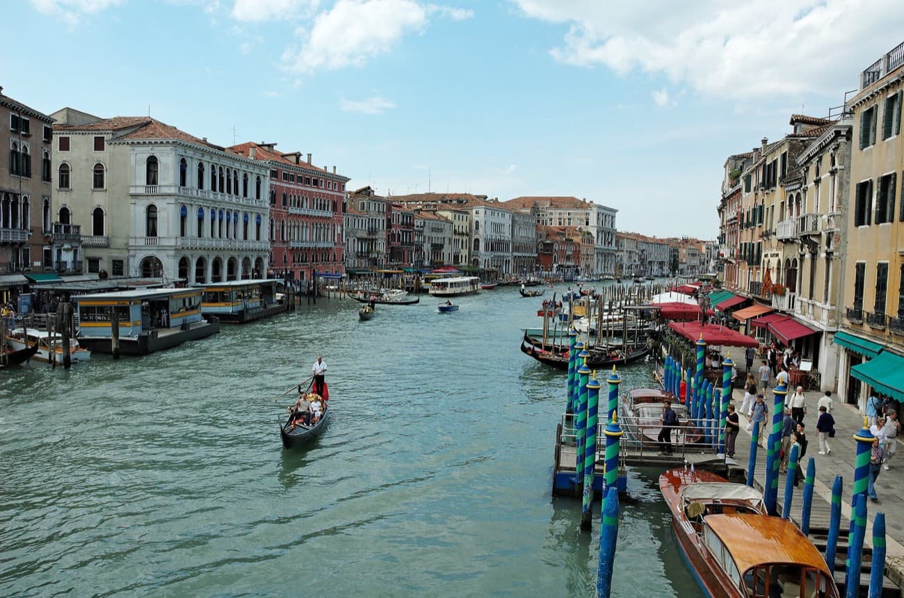 El Gran Canal de Venecia desde el puente de Rialto, con palacios a los dos lados, postes de amarre y una góndola