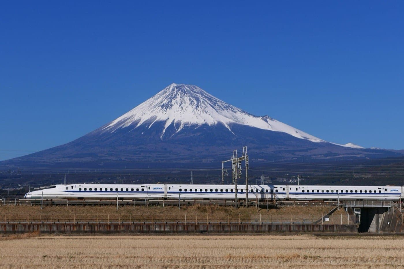 Un tren bala Shinkansen blanco pasando frente al monte Fuji nevado